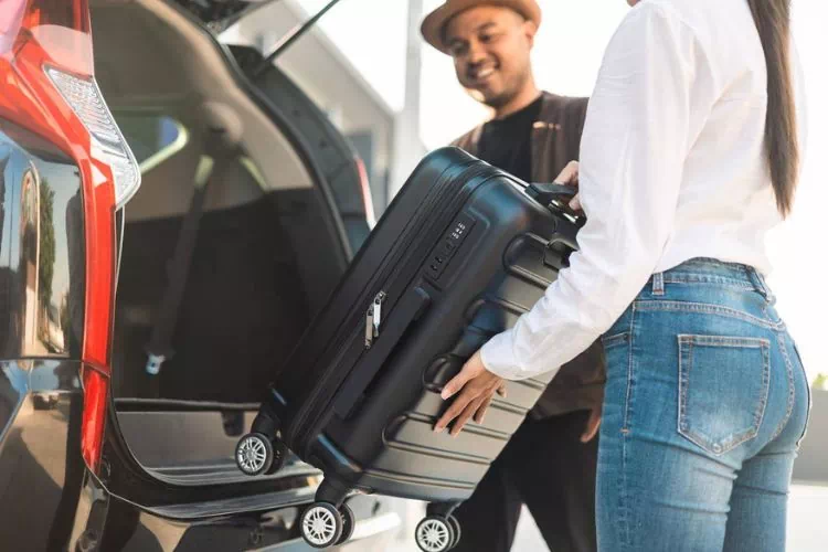 Couple mettant leurs bagages dans une voiture de location