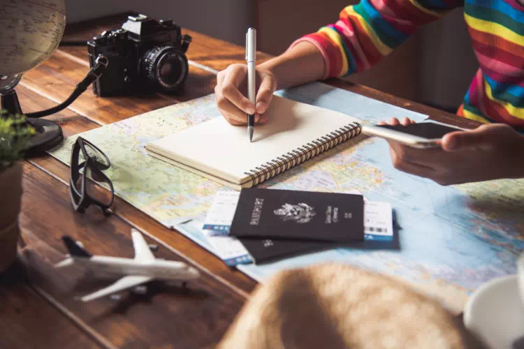 Personne rédigeant la liste des choses à faire et à prendre pour un voyage